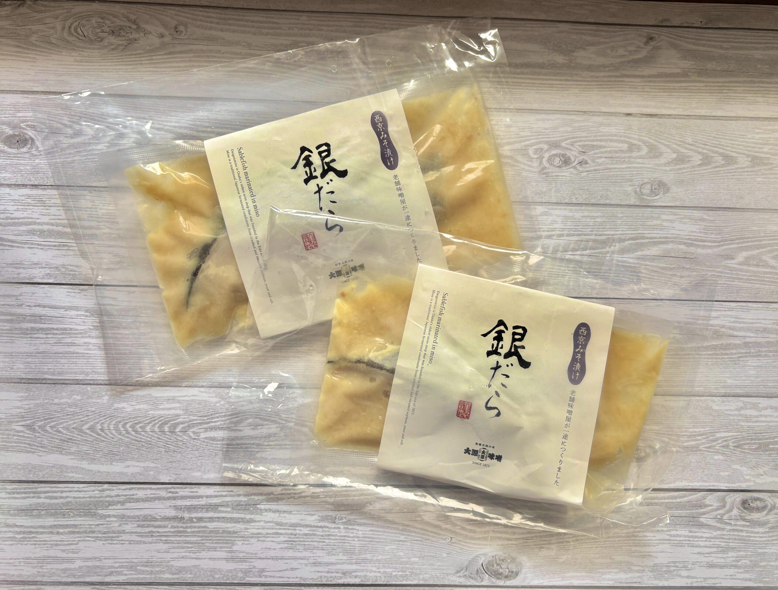 西京味噌にじっくり漬け込まれた銀鱈の切り身を真空パックで保存した状態の写真。脂ののった銀鱈と甘みのある味噌が特徴で、焼くだけ簡単に本格和食が完成する人気のお取り寄せグルメ・魚料理。