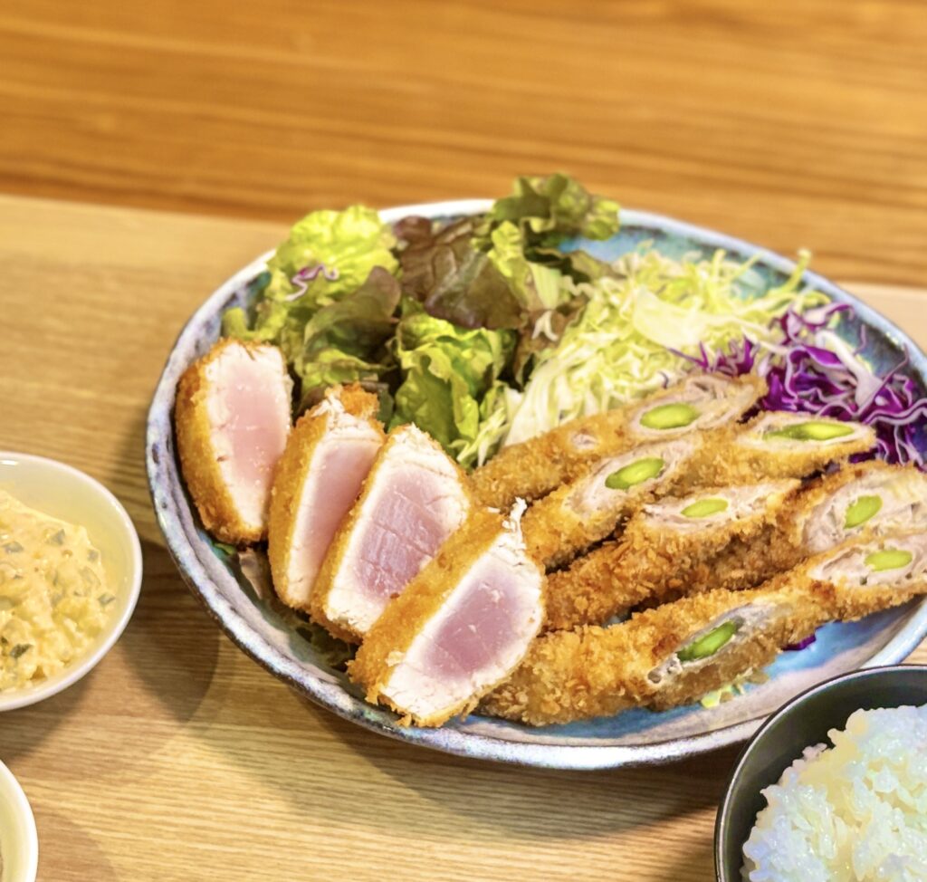 キハダマグロのレアカツの断面がロゼ色に輝く揚げたてのプレート。アスパラの豚肉巻きフライと野菜サラダを添えて
