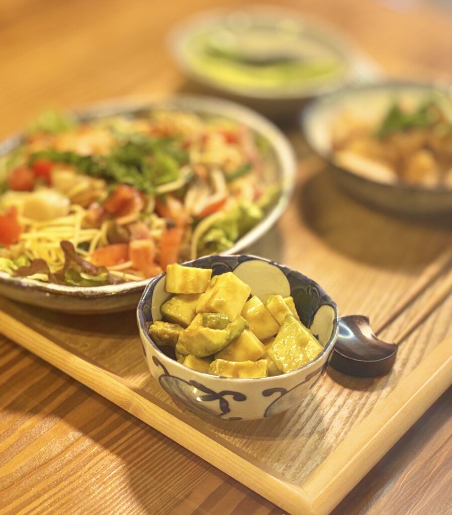 アボカドとモッツァレラチーズをワサビ醤油で和えた副菜のアップ写真。クリーミーなアボカドとミルキーなモッツァレラチーズにワサビ醤油が絡んだ、白ワインにぴったりの簡単副菜レシピ。切って和えるだけで完成する時短おつまみ。