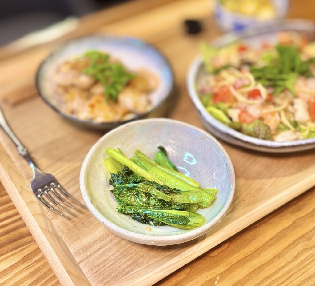 小松菜のガーリックソテーのアップ写真。にんにくの香りが食欲をそそる、白だしで味付けしたシンプルな副菜。シャキッとした食感に仕上がった小松菜のガーリック炒めは、パスタ献立の副菜としても相性抜群の簡単レシピ。