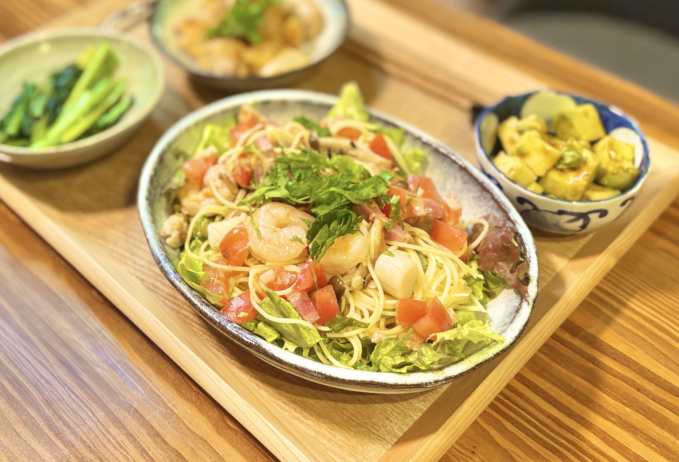 シーフードミックスと貝柱とベーコンのガーリック炒めを混ぜ込んだ冷製サラスパサラダのアップ写真。レタスを敷いた上に細めのパスタを盛り付け、トマトと青紫蘇をトッピング。味付けはピエトロドレッシングのみのシンプルレシピで、白ワインとの相性が抜群な初夏の冷製パスタ献立。