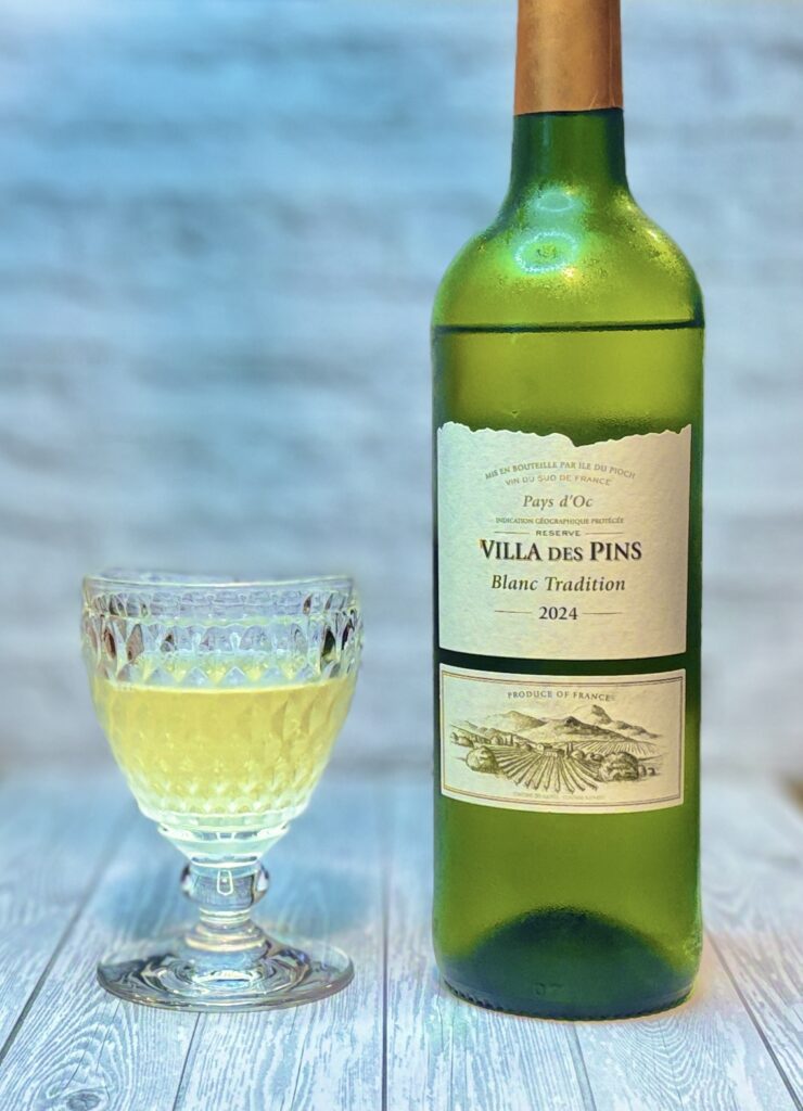 南フランス・ラングドック地方産の白ワイン「ヴィラ・デ・パン ブラン・トラディション2024（Villa des Pins Blanc Tradition 2024）」のボトルとグラスの写真。ペイ・ドックIGPの爽やかでフルーティーな白ワインで、シーフード冷製パスタや鶏料理との相性が抜群。おうちごはんに合うコスパの良いフランス白ワイン。