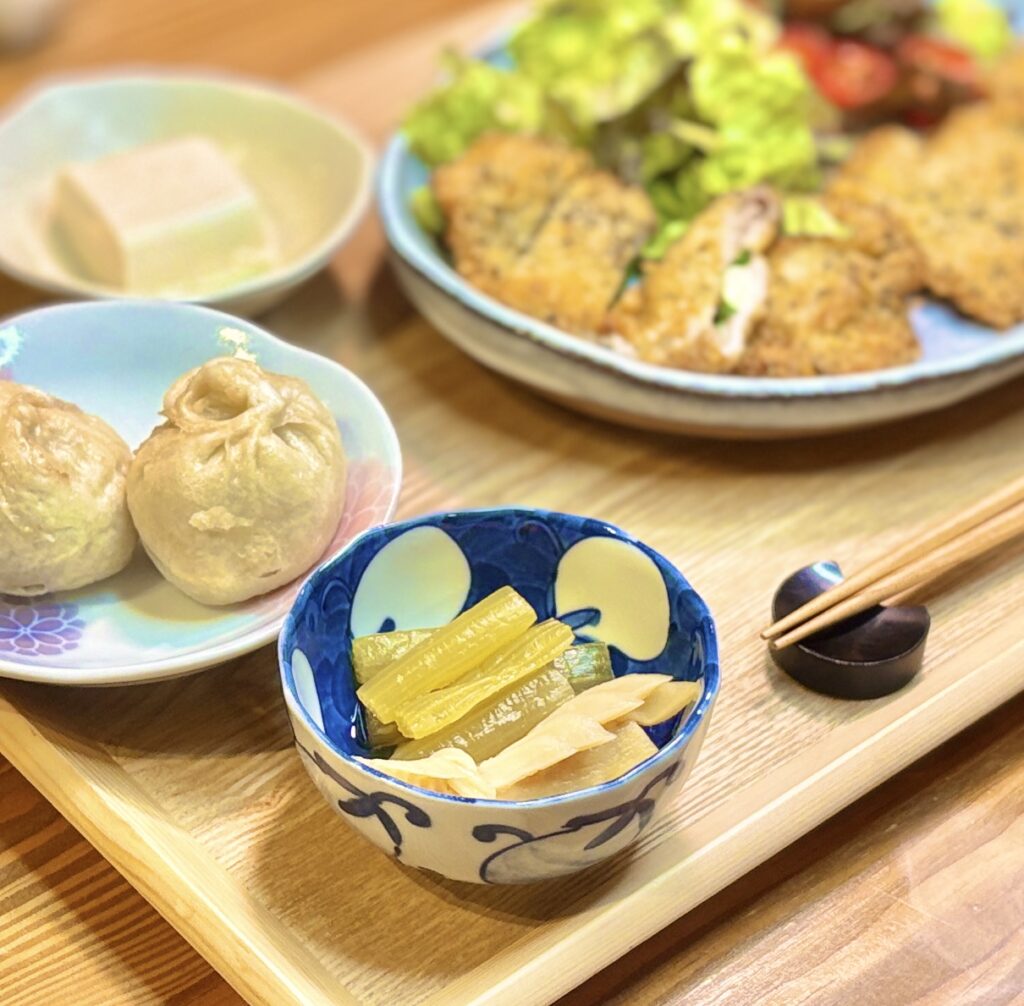 青い器に盛られたふきと筍の煮物。茅乃舎だしで仕上げたやさしい味わいの和の一品