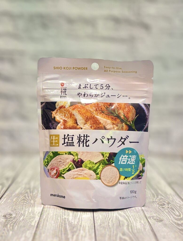 マルコメの生塩麹パウダーのパッケージ写真。肉や魚に振りかけて5分置くだけでやわらかくジューシーに仕上がる時短調味料で、トンテキやマグロのレアカツなど幅広い料理に使える万能調味料。