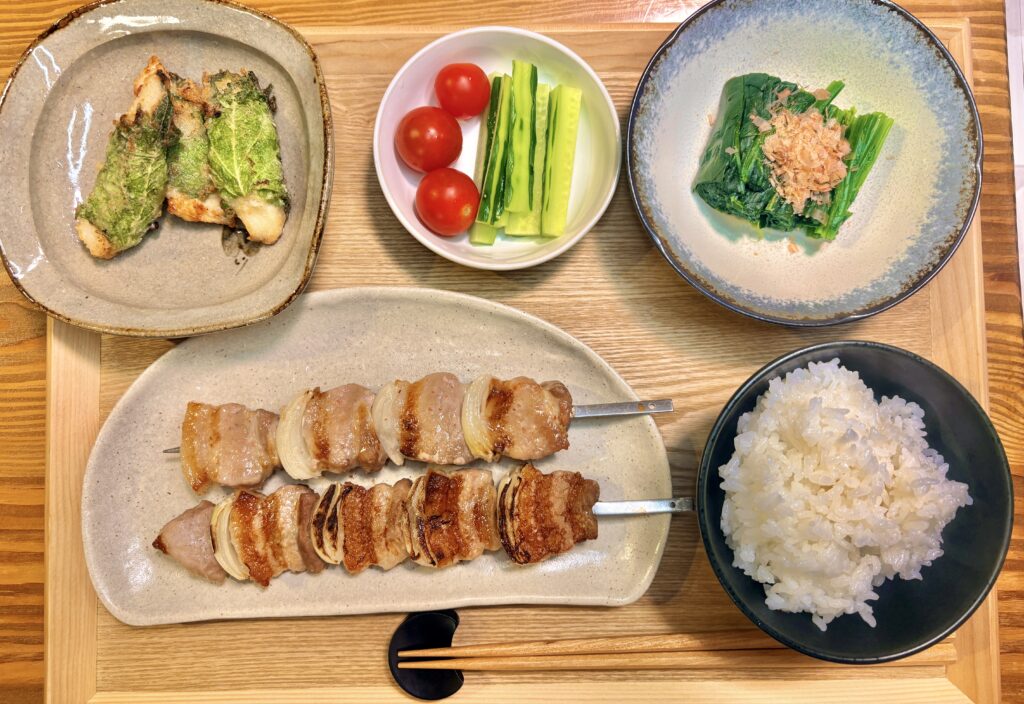 塩麹豚バラ肉の串焼きをメインに、塩麹漬け鶏胸肉の大葉巻き焼き、ほうれん草のお浸し、きゅうりスティックとミニトマトを添えた和風献立。マルエフに合うおうち居酒屋ごはんの全体写真。