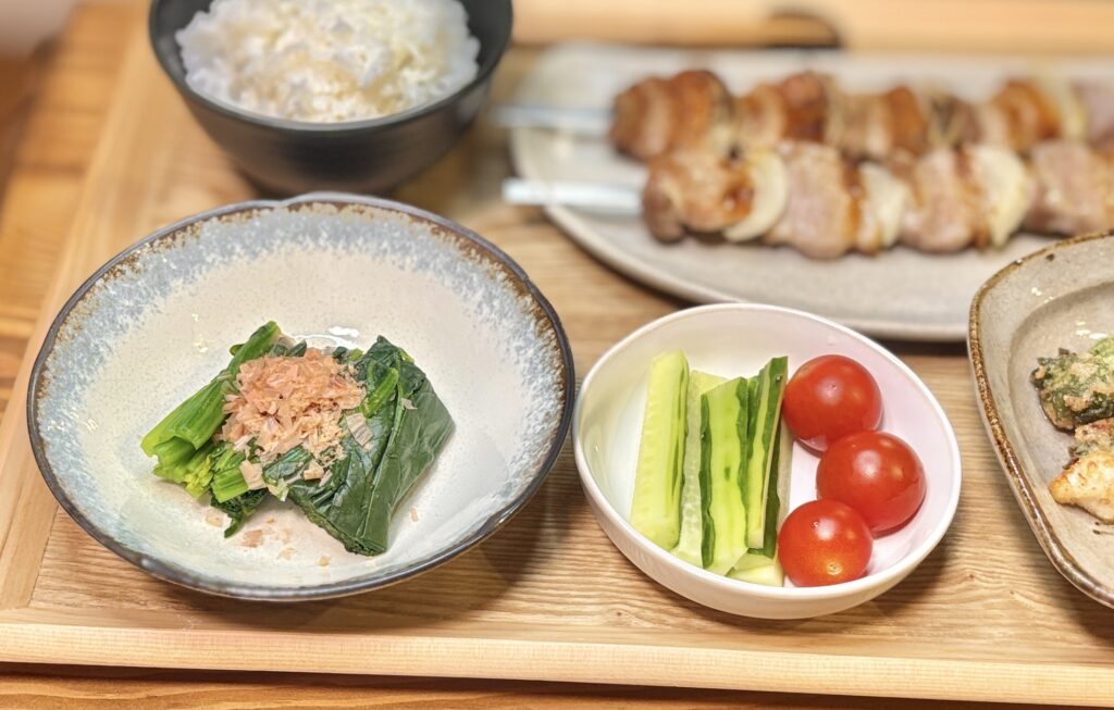 かつお節をのせたほうれん草のお浸しと、きゅうりスティック・ミニトマトのシンプル副菜。箸休めにぴったりなさっぱり野菜おかずで、焼き物との相性も抜群。