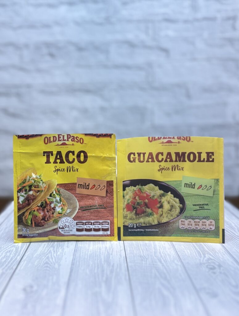白い背景の前に並んだOld El PasoのTaco Spice MixとGuacamole Spice Mixの黄色いパッケージ。タコス料理の味付けに使うシーズニングミックス。