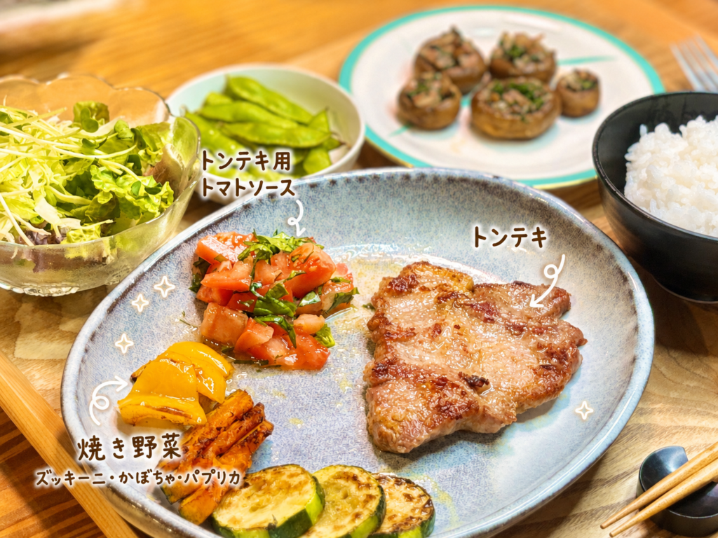 香ばしく焼いたトンテキに、刻んだトマトと紫蘇を合わせたさっぱりソース、ズッキーニ・かぼちゃ・パプリカの焼き野菜を添えた一皿。手書き風の文字入れでトンテキ用トマトソースと焼き野菜を紹介した、暑い日に食べやすいトンテキ献立の写真。