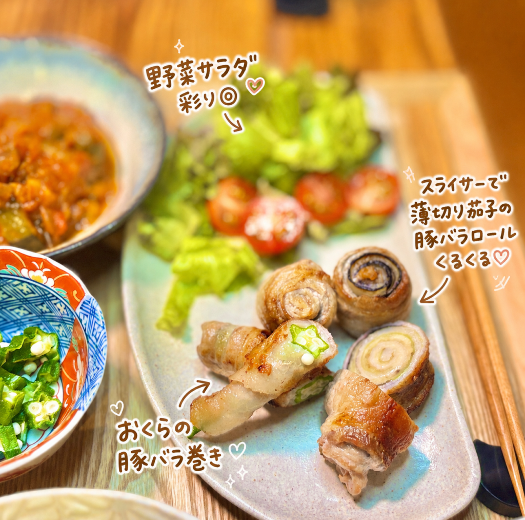 薄切り茄子の豚バラロール、おくらの豚バラ巻き、野菜サラダを一皿に盛り付けた旦那キッチンの晩ごはん写真。豚バラ巻きは香ばしく焼き上がり、茄子の断面やおくらの星形が見える見た目も楽しいおかず。レタスやミニトマトを添えた野菜サラダで彩りを加え、肉料理と野菜をバランスよく楽しめるおうちごはんの一枚。