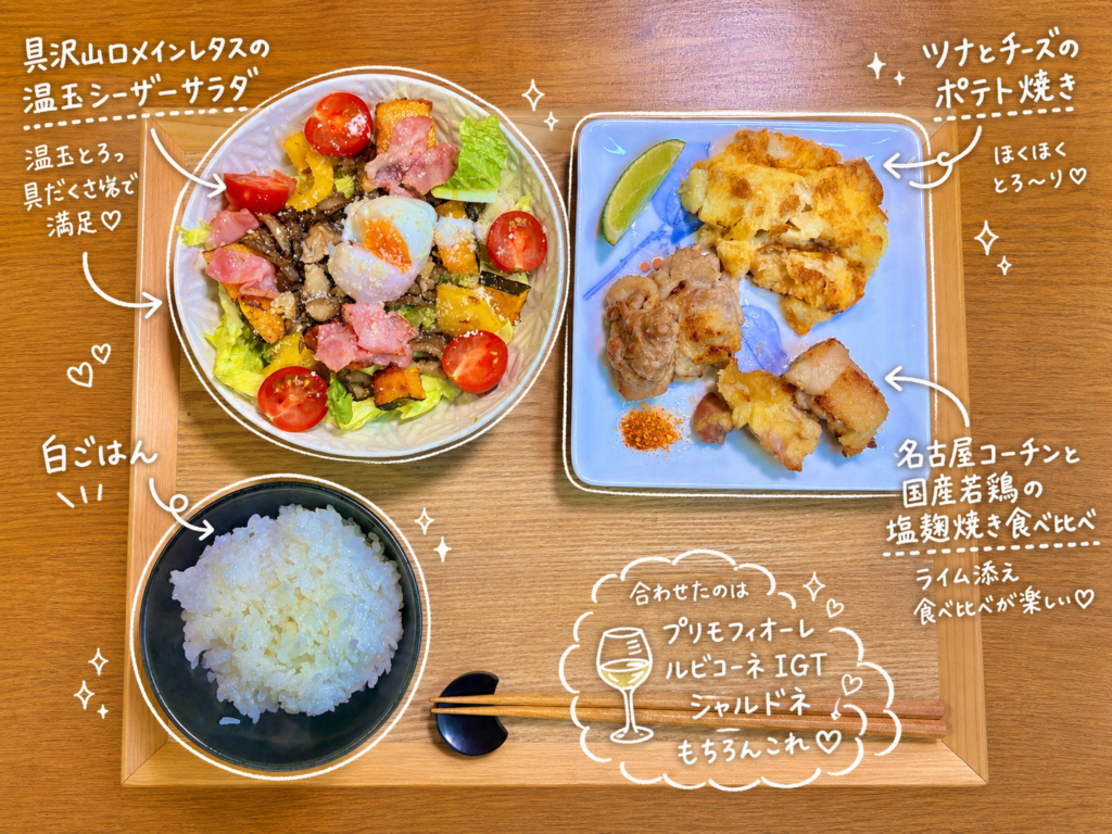 名古屋コーチンと国産若鶏の粉塩麹焼き食べ比べ、ツナチーズポテト焼き、具沢山ロメインレタスの温玉シーザーサラダ、白ごはんを木製トレーに並べた晩ごはん献立。ライムを添えた塩麹チキンと白ワインに合う家庭料理の食卓。