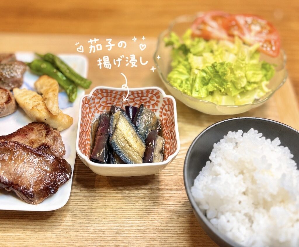 ラムステーキと厚切り牛タン焼き、鶏胸肉のソテーを主役に、ししとう、小松菜のガーリック炒め、茄子の揚げ浸し、野菜サラダを合わせた晩ごはん献立。サントリー生ビールにも合う、家庭料理のお肉プレートを手書き風に紹介した加工画像。