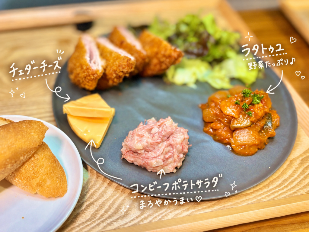 黒いプレートにラタトゥユ、コンビーフポテトサラダ、チェダーチーズを盛り付けた、洋風晩ごはんの副菜プレート。トマトの旨みと野菜の甘みが詰まったラタトゥユ、まろやかなコンビーフポテトサラダ、コクのあるチェダーチーズを、白い手書き文字と矢印で可愛く紹介している。コルドンブルーやバゲット、白ワインにも合わせやすいおうちビストロ風の副菜写真。
