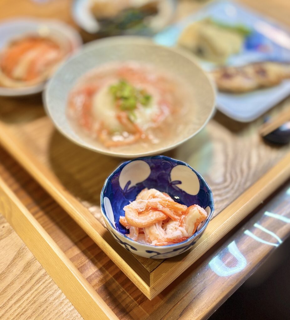 紅ズワイのカニ身蟹酢和えを主役に、紅ズワイカニのあんかけ豆腐や自家製サワラの西京味噌漬け、タケノコとししとうの天ぷらを合わせた贅沢和食献立の写真。