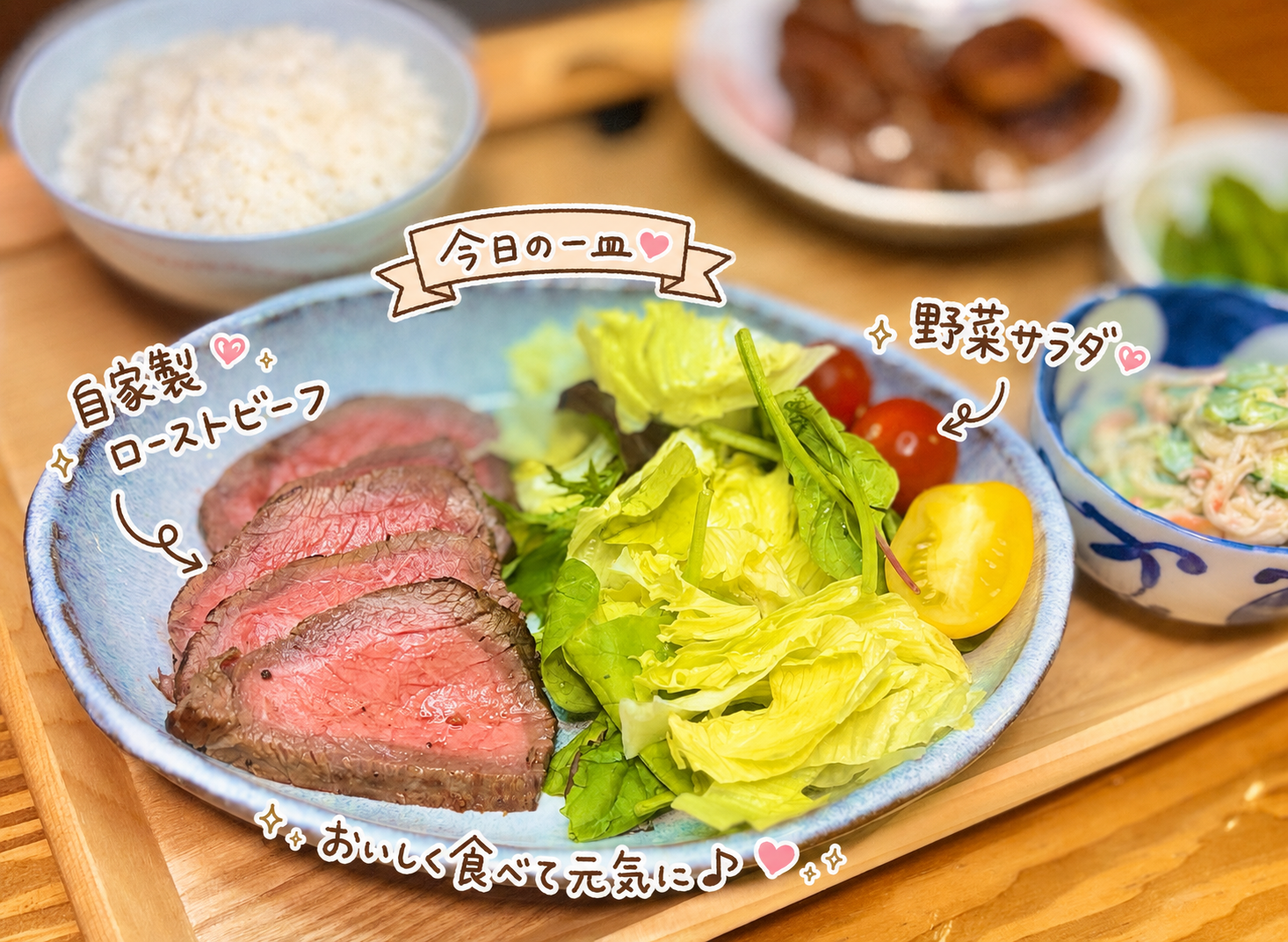 自家製ローストビーフと野菜サラダを大皿に盛りつけた写真。しっとり焼き上げたローストビーフにレタスやミニトマトを添え、旦那キッチンの今日の一皿として手書き風の文字で紹介している。