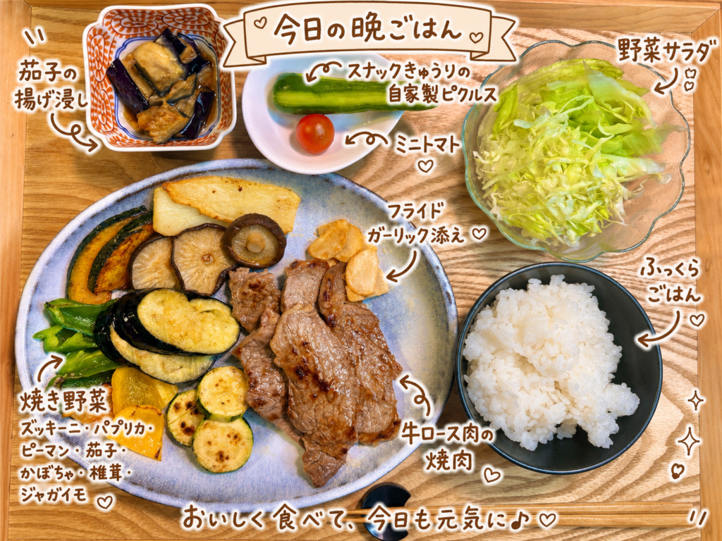 牛ロース肉の焼肉、フライドガーリック、ズッキーニやパプリカなどの焼き野菜、茄子の揚げ浸し、自家製ピクルス、野菜サラダ、白ごはんを木製トレーに並べた晩ごはん献立。