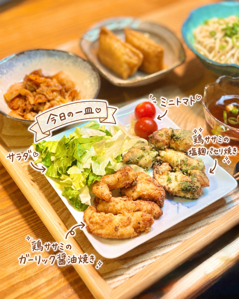 白いプレートに鶏ササミのガーリック醤油焼き、鶏ササミの塩麹パセリ焼き、サラダ、ミニトマトを盛り付けた写真。さっぱりした冷やしうどん献立に、たんぱく質と彩りを添えるおかずプレート。