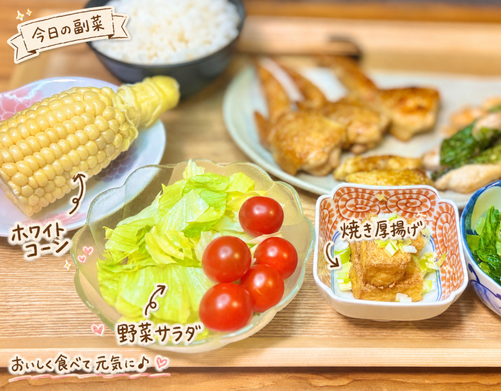 ホワイトコーン、野菜サラダ、焼き厚揚げを手前に並べた副菜写真。鶏肉メインの献立に合わせた、彩りのよい副菜を手書き風の文字で可愛く紹介している。