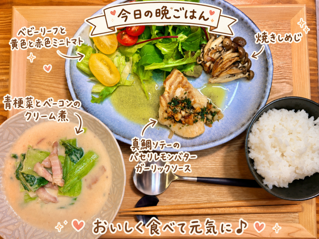 真鯛ソテーのパセリレモンバターガーリックソース、青梗菜とベーコンのクリーム煮、焼きしめじ、ベビーリーフと黄色・赤色ミニトマト、白ごはんを木のトレーに並べた旦那キッチンの洋風晩ごはん献立写真。手書き風の文字で料理名を可愛く紹介している