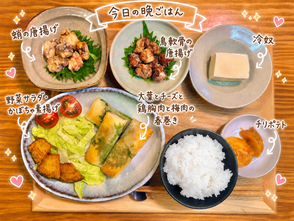 蛸の唐揚げ、鳥軟骨の唐揚げ、冷奴、大葉とチーズと鶏胸肉と梅肉の春巻き、野菜サラダとかぼちゃ素揚げ、チリポテト、白ごはんを木製トレーに並べた旦那キッチンの晩ごはん。手書き風の文字入れでメニュー名を紹介した、家族で巻き巻きして作った春巻き献立の全体写真。