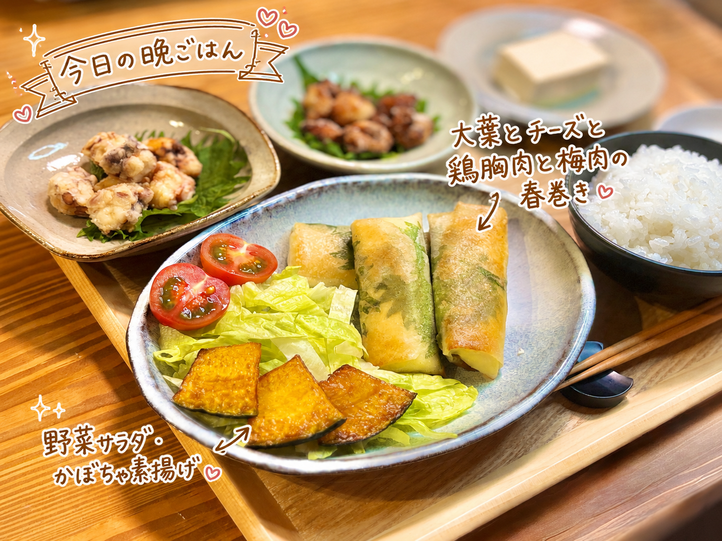 大葉とチーズ、鶏胸肉、梅肉を包んだ春巻きに、野菜サラダとかぼちゃ素揚げを添えた一皿。手書き風の文字と矢印で春巻きと付け合わせを紹介した、家族で作る手巻き春巻き献立の一品写真。