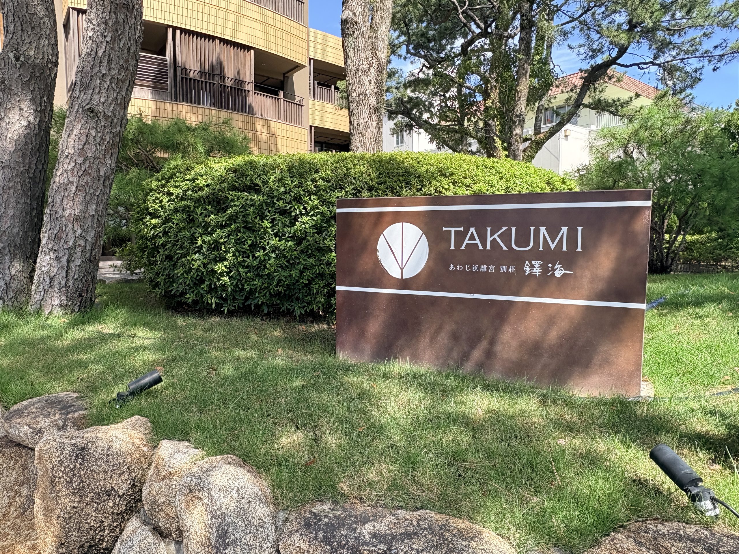 淡路島の宿「あわじ浜離宮 別荘 鐸海（TAKUMI）」の入口看板。緑と松に囲まれた落ち着いたリゾート旅館