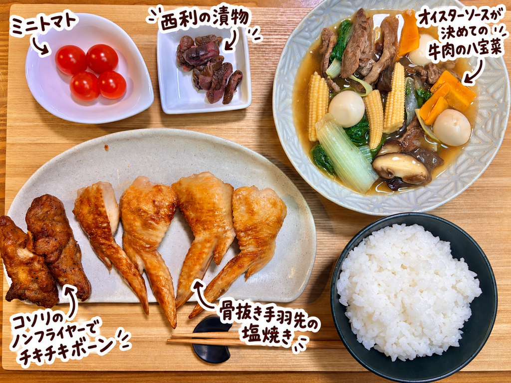 オイスターソースが決め手の牛肉の八宝菜、骨抜き手羽先の塩焼き、コソリのノンフライヤーで温めたチキチキボーン、西利の漬物、ミニトマト、白ごはんを並べた旦那キッチンの晩ごはん献立