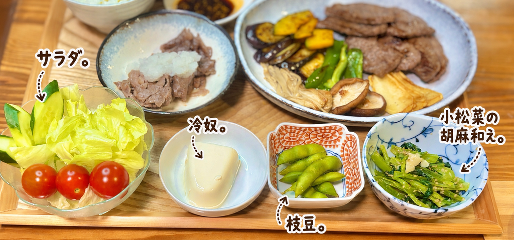 小松菜の胡麻和え、枝豆、冷奴、レタス・きゅうり・ミニトマトのサラダを並べた焼肉の副菜。野菜と豆腐を組み合わせた、焼肉に合うさっぱり簡単副菜の盛り合わせ